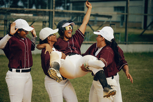 Baseball team celebrates a home run with joyful energy as a player is lifted in the air