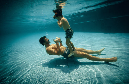 Father and son bonding underwater in a swimming pool