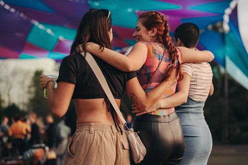 Three female friends embracing as they come together for a blissful summer festival experience