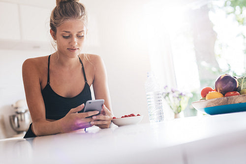 Young woman using mobile phone in kitchen