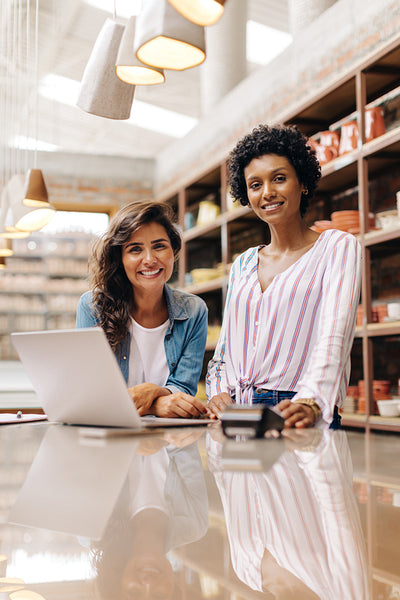 Happy female entrepreneurs smiling at the camera in their ceramic shop