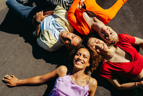 Lying friends smile together outdoors in an urban circle formation
