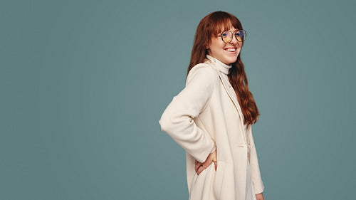 Cute young woman with glasses smiling in a studio