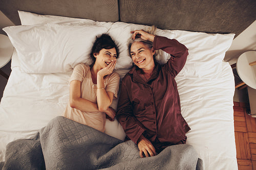 Senior woman lying on bed with her daughter and talking