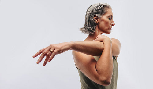 Woman stretching arm across chest in studio