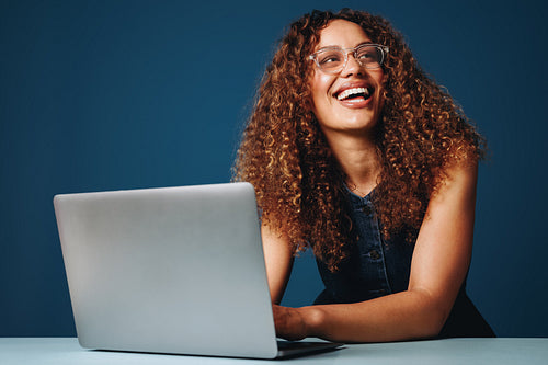 Monochromatic studio shot of female entrepreneur working on laptop