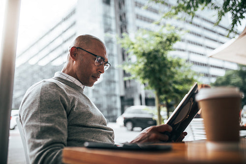 Businessman sitting at a restaurant reading book.