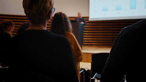 Business conference in action: Business woman engaging in a seminar led by a senior business man