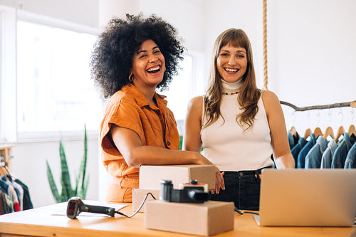 Happy clothing store owners smiling at the camera in their shop