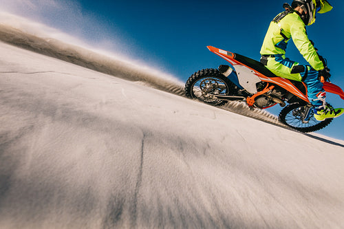 Motocross biker racing in sand dunes