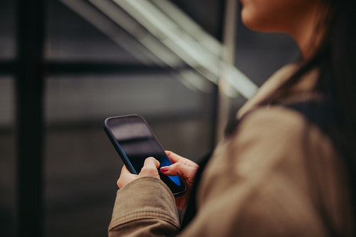 Woman using smartphone while waiting on subway platform