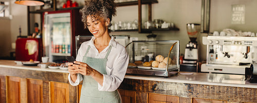 Cafe owner using a smartphone in her shop