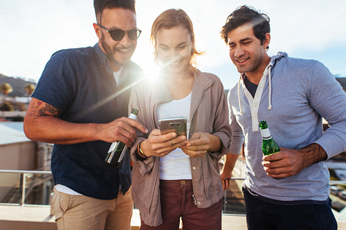 Friends at rooftop party using mobile phone
