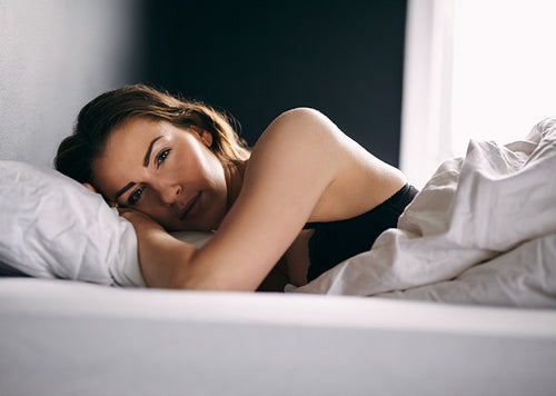 Young woman lying in bed daydreaming