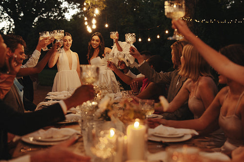 Celebration at an intimate garden wedding with guests toasting under outdoor lights