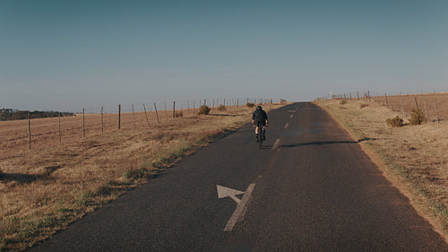 Sportsman cycling uphill on a long countryside highway