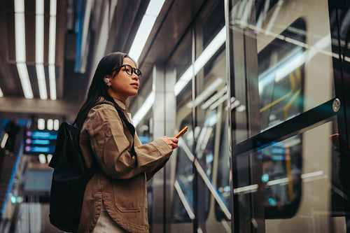 Commuter woman waiting at train station with phone