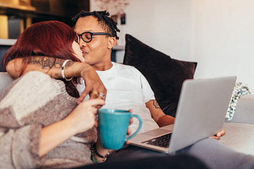 Romantic couple sitting on sofa with laptop