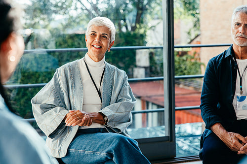 Mature female employer smiling and listening while engaging with team in a casual meeting