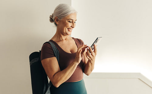 Senior woman using a fitness app for her yoga routine at home