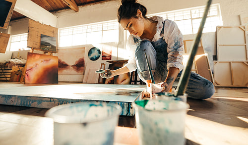 Artist painting on a canvas on the floor
