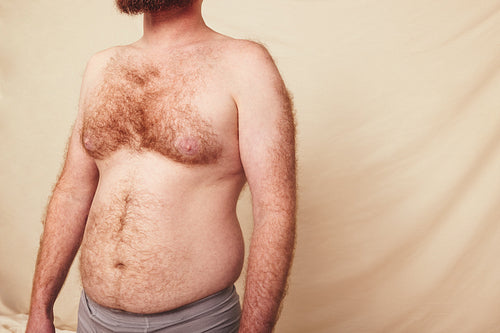 Hairy man with a pot belly standing in a studio
