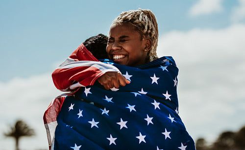 American female athletes with flag hugging each other after a win