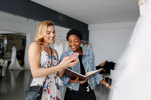 Bride showing a wedding dress design to bridal shop owner
