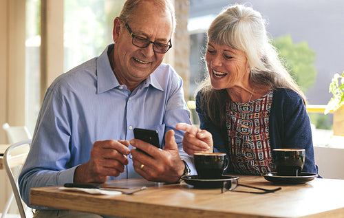 Senior couple using mobile phone at a cafe