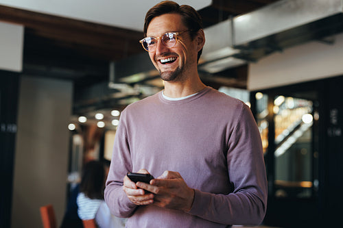 Male professional holding a mobile phone in an office