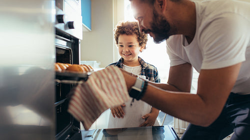Man taking out baked cookies from an oven