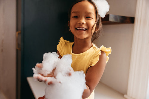 Adorable little girl playing with bubbles at home