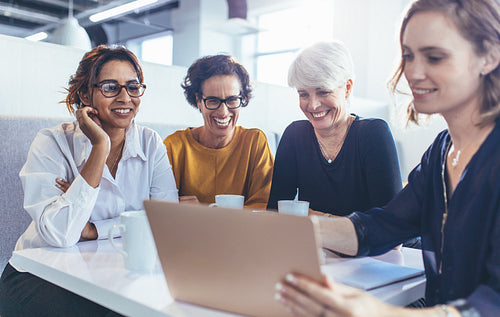 Team of female professionals in cafeteria with a laptop