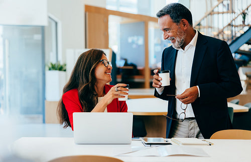 Two senior executives enjoying coffee while talking at a workplace