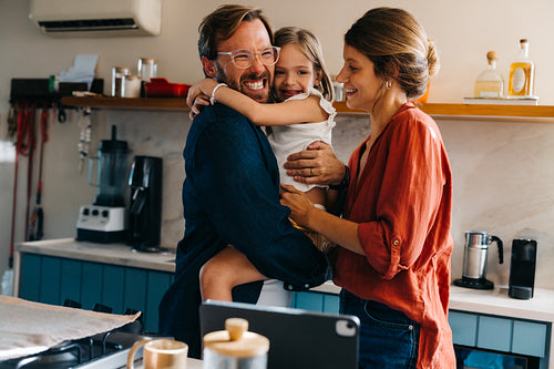 A family hugs in a sunny kitchen at home