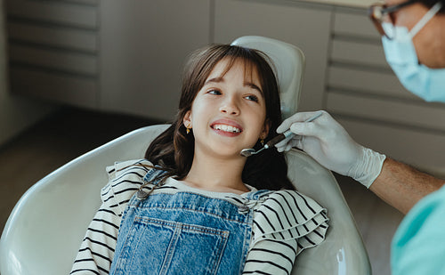 Young girl sits with a dentist for oral care during a pediatric clinic visit