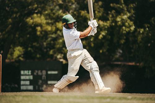 Cricket player in full swing performing a powerful batting move outdoors