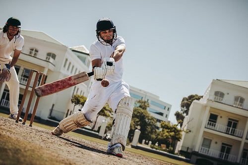 Cricket batsman playing a shot during a match on a sunny day