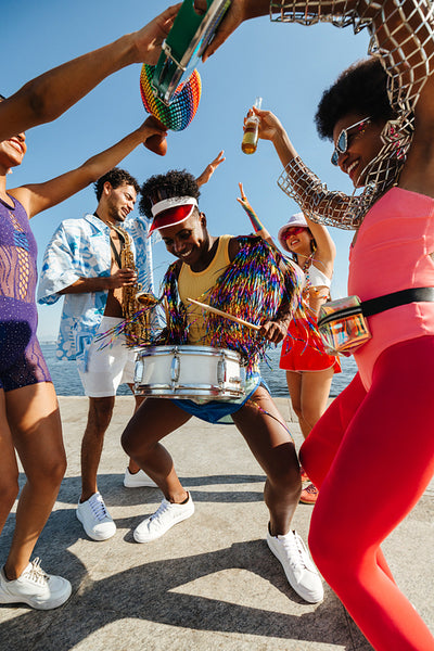 Friends celebrate with bright carnival drum on beach