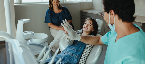 Dentist and child share a high five in a family clinic after the checkup