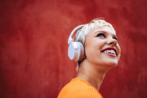 Young edgy woman wears headphones and smiles in a studio music portrait