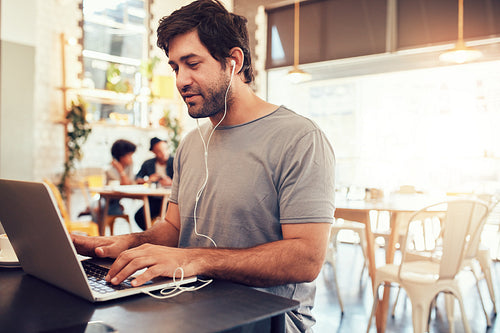 Young guy at a cafe surfing internet on laptop