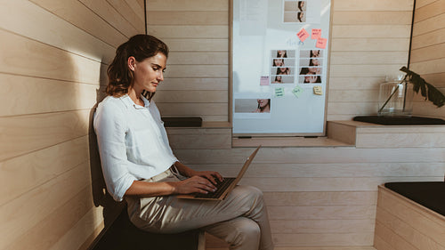 Businesswoman sitting in creative office working on laptop