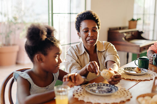 Mother serving her daughter with cheese bread rolls on a Brazilian breakfast table