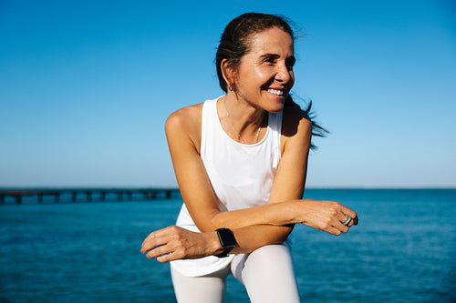 Smiling woman standing by the sea enjoying the sunny outdoors