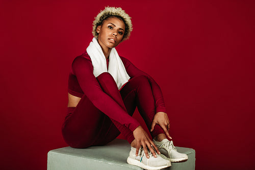 Female athlete sitting on exercise block after workout