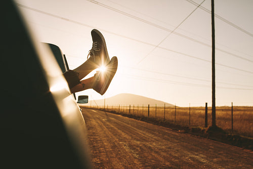 Legs hanging out of a car on highway