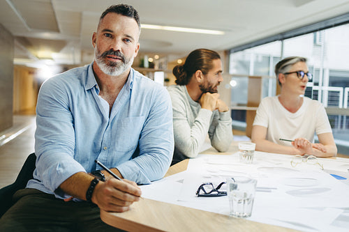 Mature achitect sitting in a meeting with his team