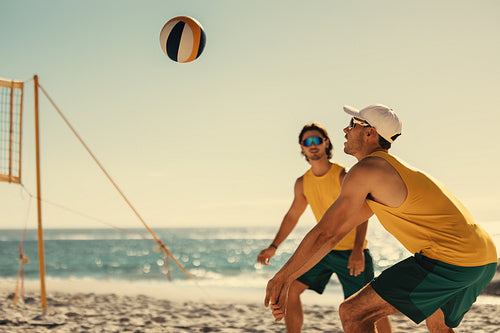 Pro volleyball players engage in intense beach match at sunset