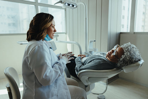 Dental chair conversation with older patient in clinic treatment room